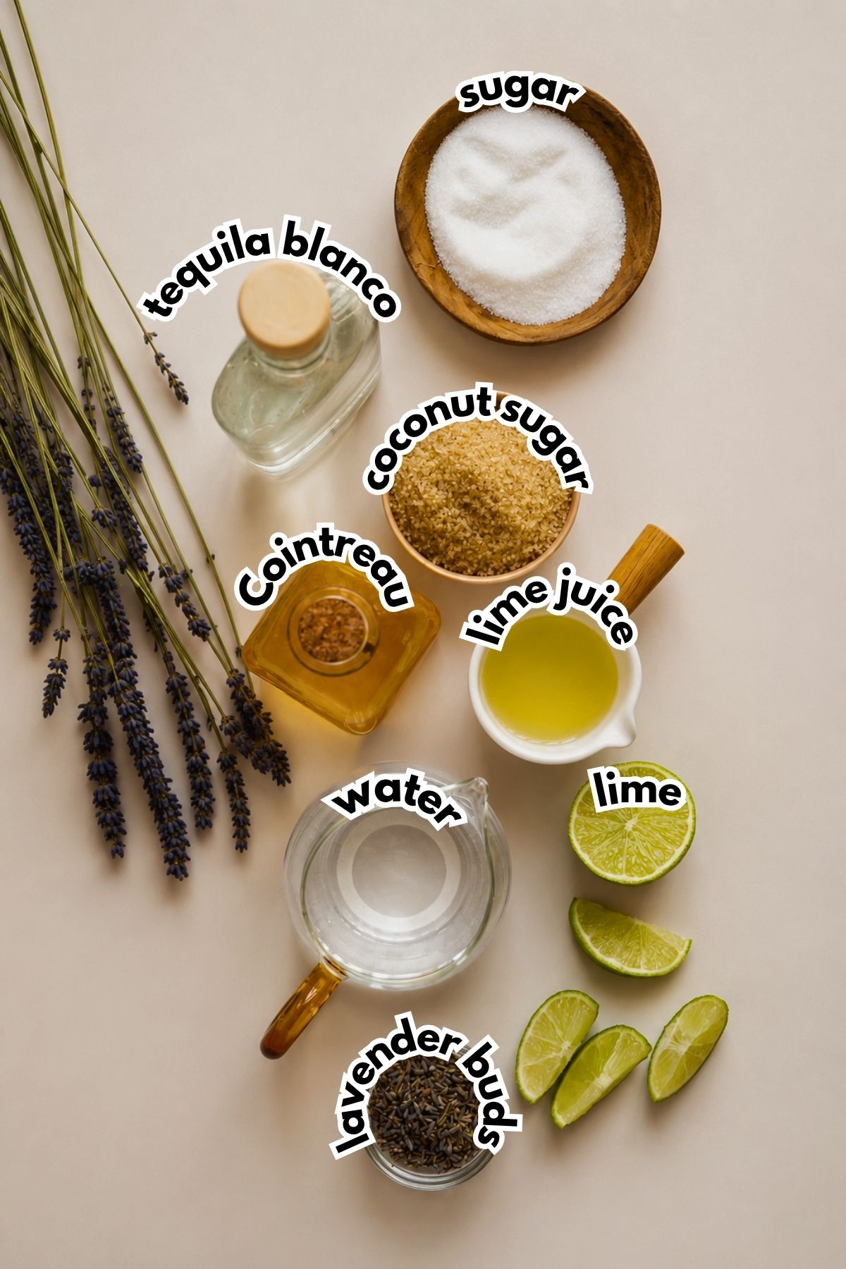 Overhead view of labeled ingredients for a cocktail: tequila blanco, sugar, coconut sugar, Cointreau, lime juice, lime, water, and lavender buds.