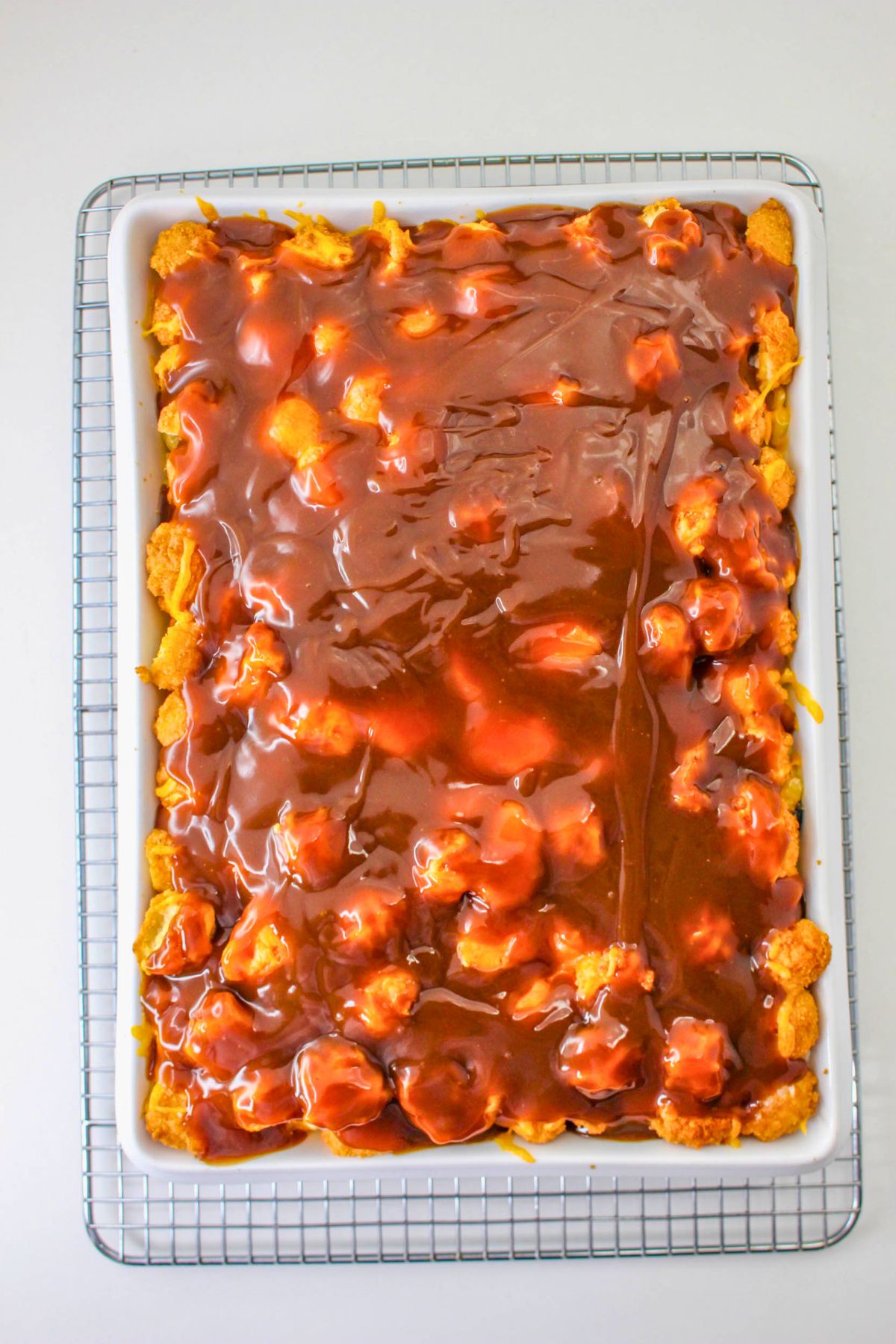 Rectangular baking dish filled with baked dessert topped with a glossy caramel or butterscotch sauce, placed on a wire cooling rack.