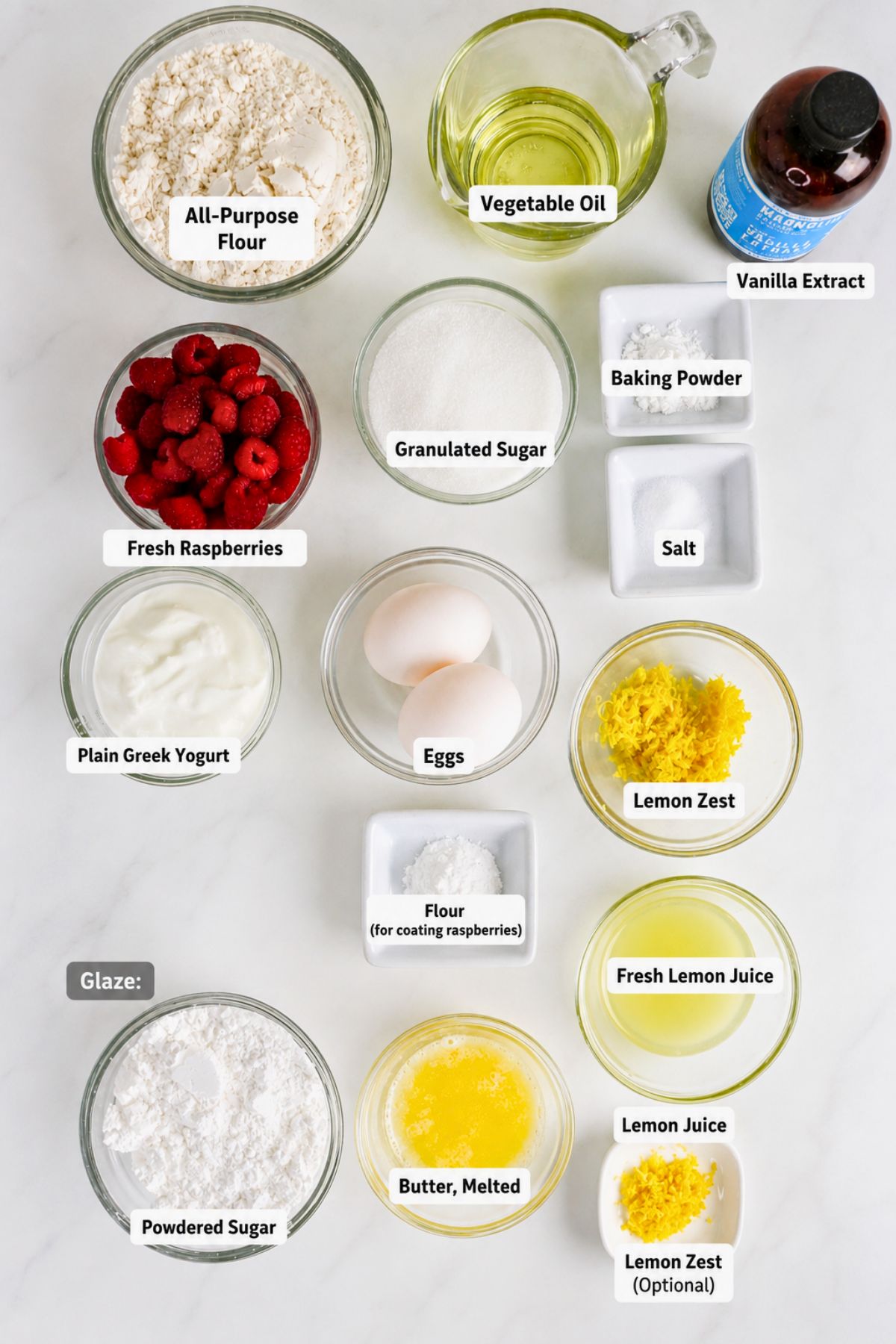 Ingredients for a raspberry lemon loaf are arranged in bowls, including flour, sugar, oil, yogurt, egg, raspberries, lemon zest, lemon juice, baking powder, salt, and optional glaze ingredients.