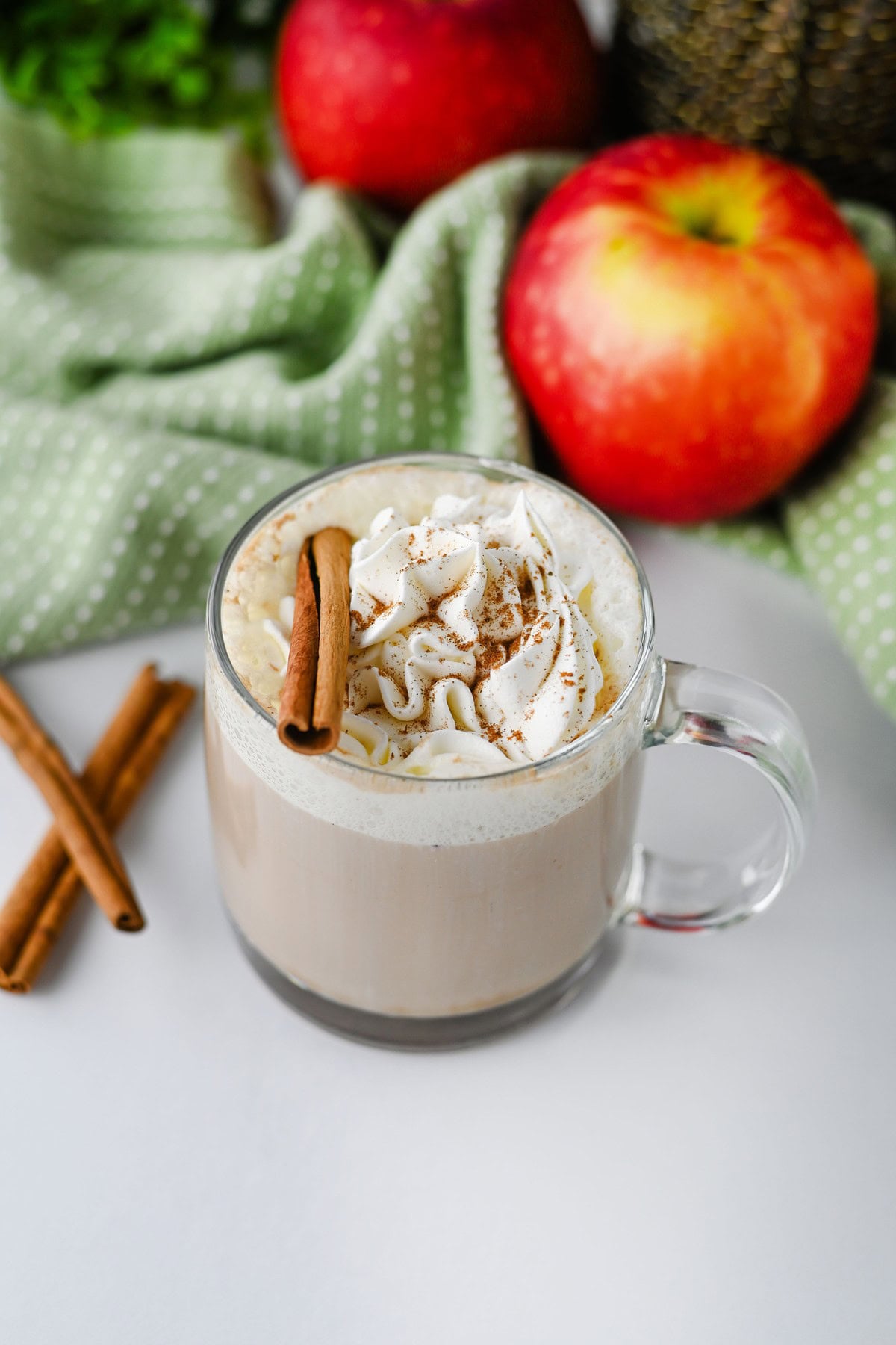 Close-up of apple chai latte with whipped cream and spice dusting in a glass mug