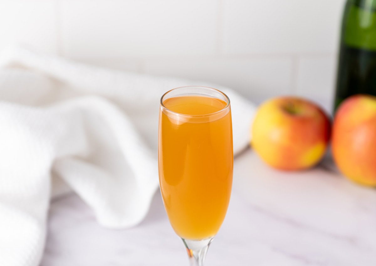 Apple Cider Mimosas horizontal shot with autumn leaves and cinnamon sticks