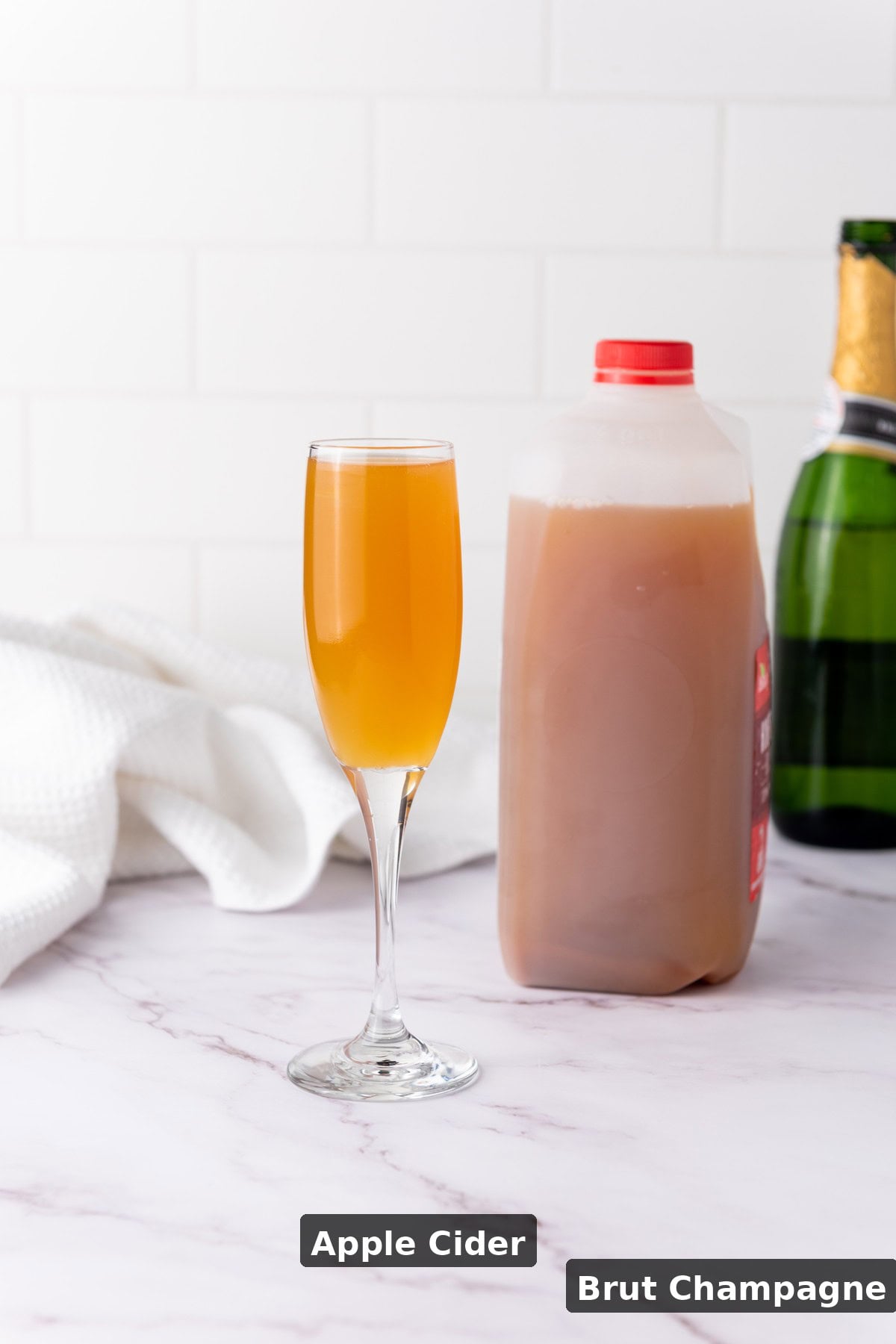 Ingredients for Apple Cider Mimosas laid flat on a wooden surface with labels