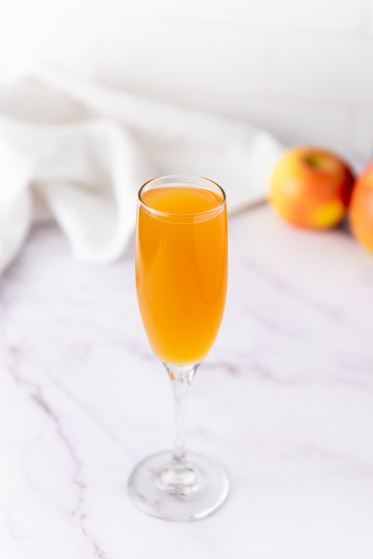 Slowly pouring fresh apple cider down the side of a champagne flute