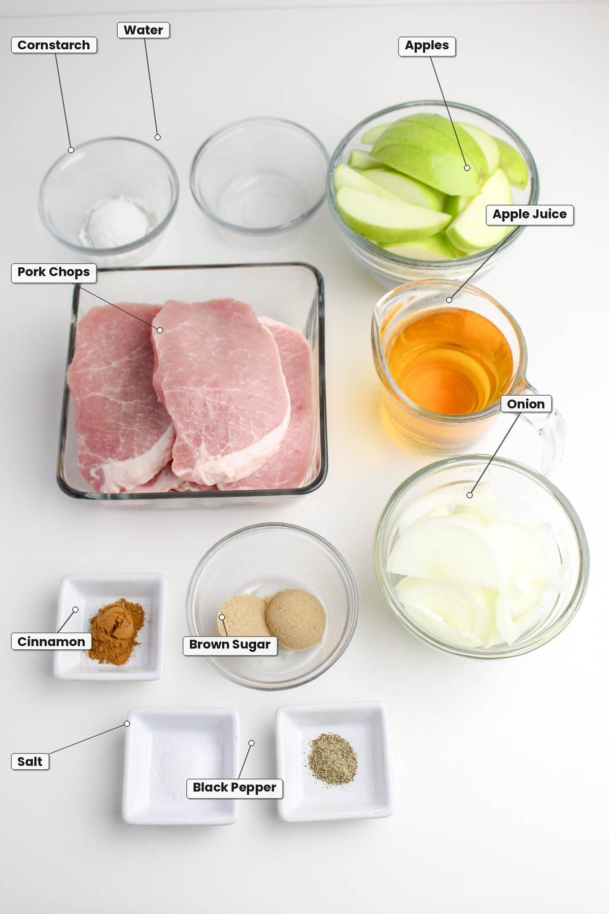 Ingredients for crockpot apple pork chops: pork chops, apple slices, apple juice, sliced onions, water, cornstarch, cinnamon, brown sugar, salt, and black pepper