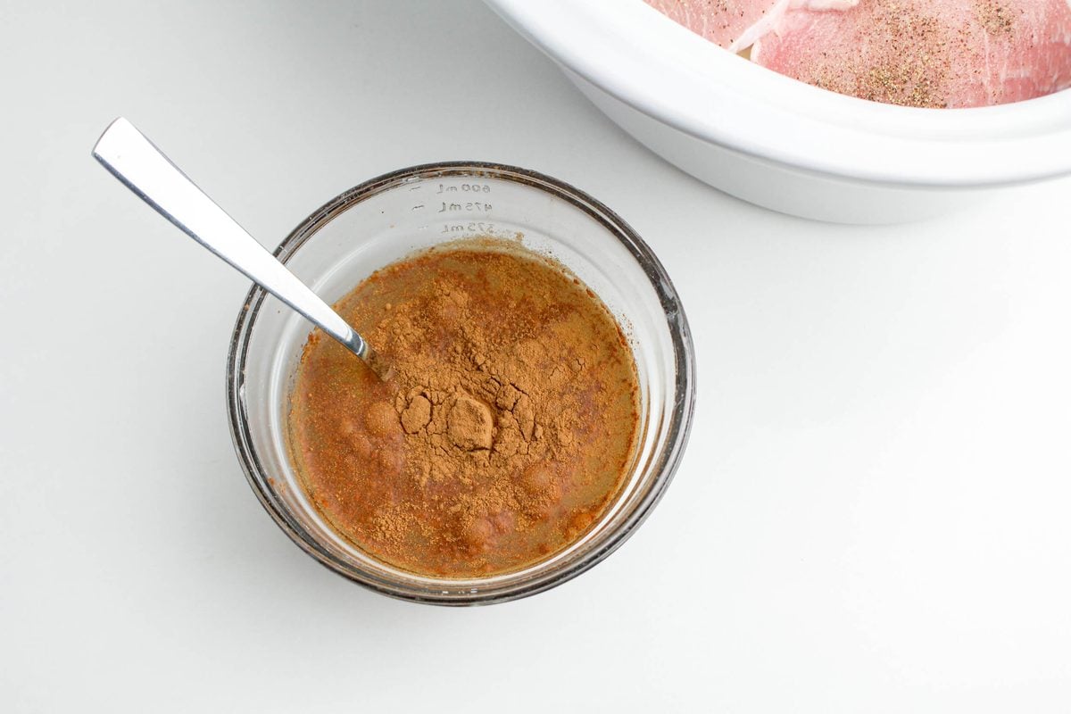 Step 3 for crockpot apple pork chops: stirring together the brown sugar, cinnamon, and apple juice sauce in a glass bowl