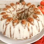 Bundt cake with white icing and a ring of pecans on top.