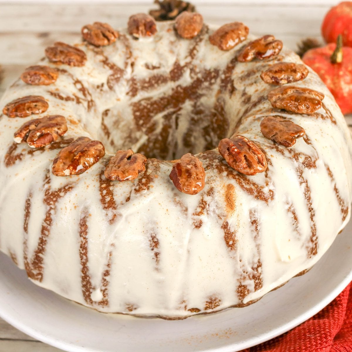 Bundt cake with white icing and a ring of pecans on top.